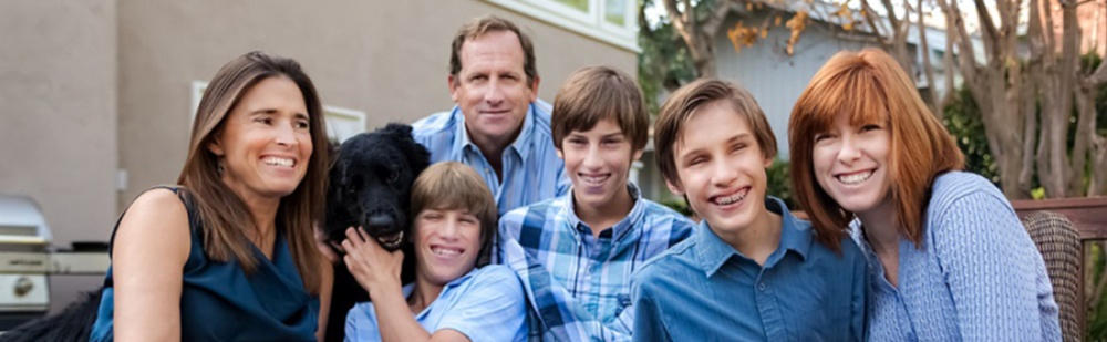 A képen egy derűs család látható: anya, apa, három látássérült fiú, lánytestvérük és egy fekete labrador