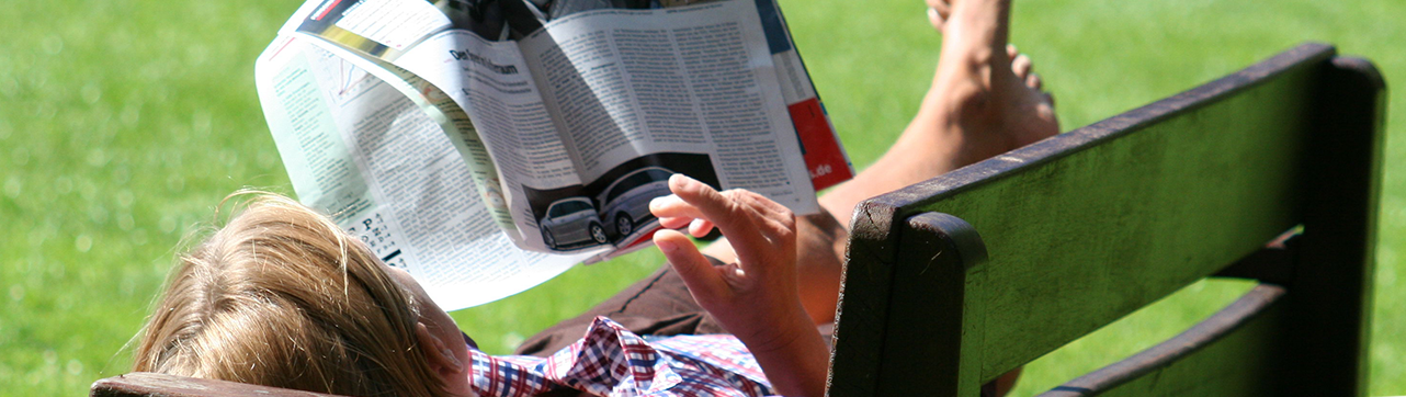 A Lapról hangra oldal nyitó képe, egy férfi egy padon fekve újságot olvas